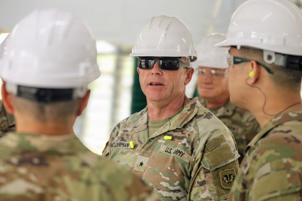 Wisconsin Army National Guard Commander Brig. Gen. Brion J. Aderman, wearing a hard hat and sunglasses, speaks with U.S. Army Soldiers at an Igam Barracks renovation site during Exercise Tamiok Strike 26